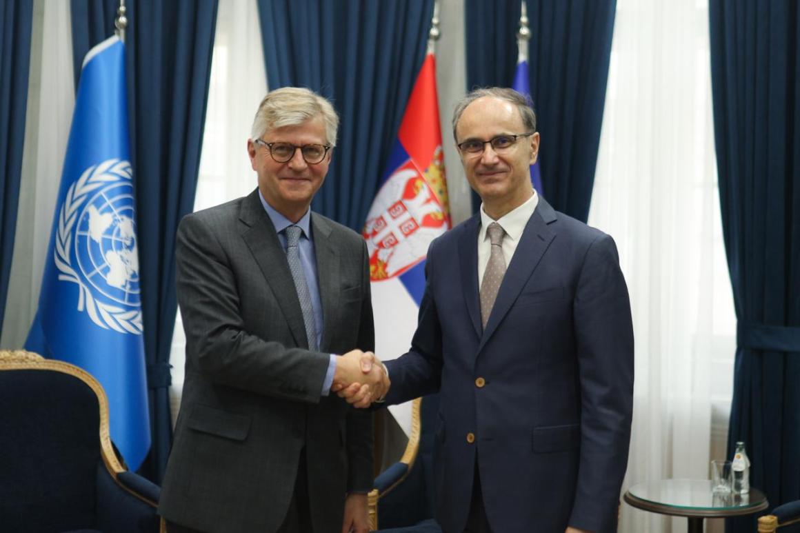 Two men shaking hands in front of flags 